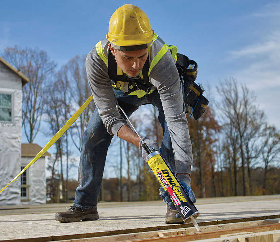 A man outdoors in a hard hat applying adhesive.