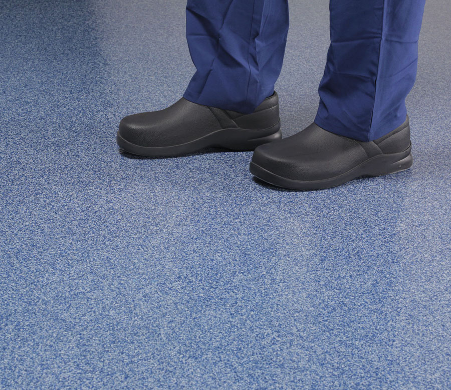 A person in boots standing on a coated floor.