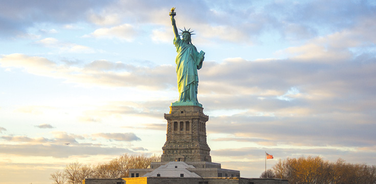 Statue of Liberty with sunset in the background.