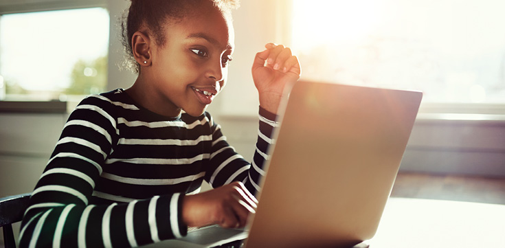 Young girl in striped shirt using a laptop.
